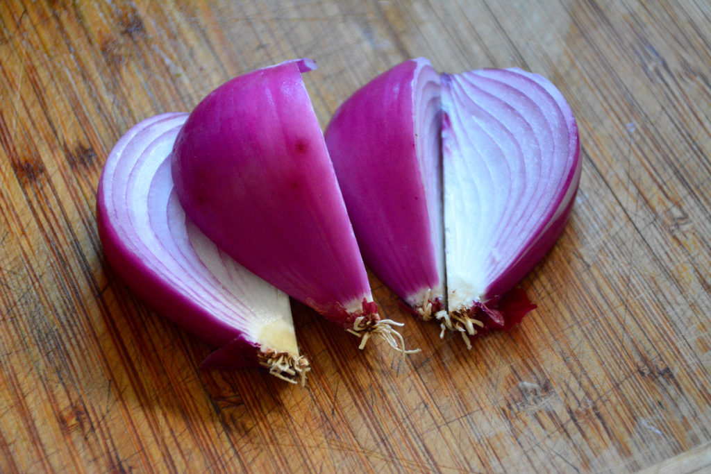 Red onion sliced into quarters with root end in tact